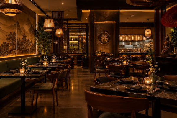 Interior of an upscale Pan-Asian restaurant in Bangalore with low warm lighting, set tables, Asian decor and a calm atmosphere