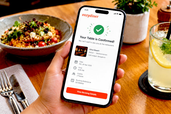 A close up of a smartphone screen displaying a confirmed restaurant reservation notification with a green checkmark in a casual dining setting