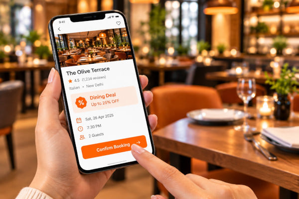 Hand tapping a confirm booking button on a phone screen, dining deal badge visible, restaurant interior blurred in background, warm evening lighting